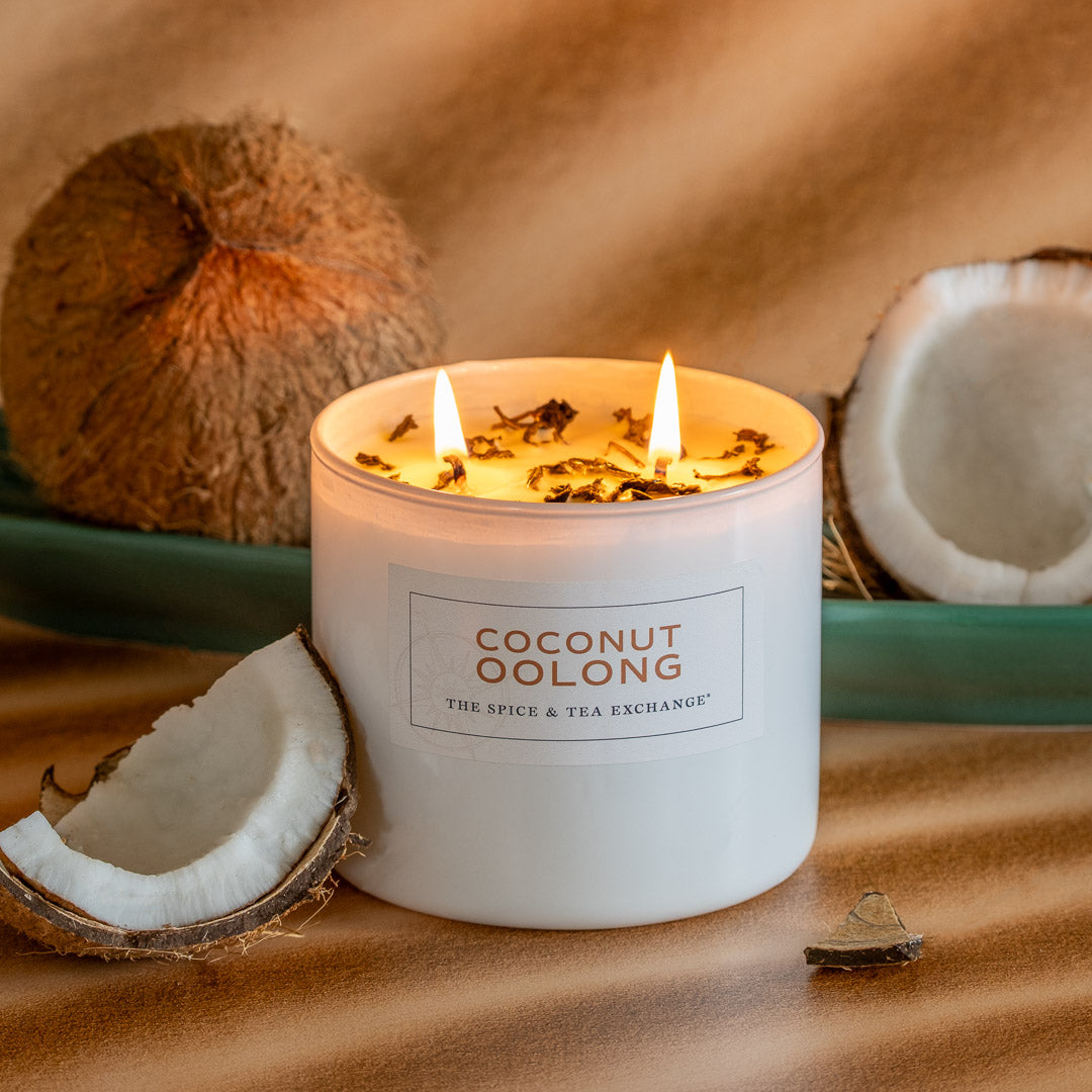 Coconut Oolong Candle on brown countertop with a teal tray and coconuts around it